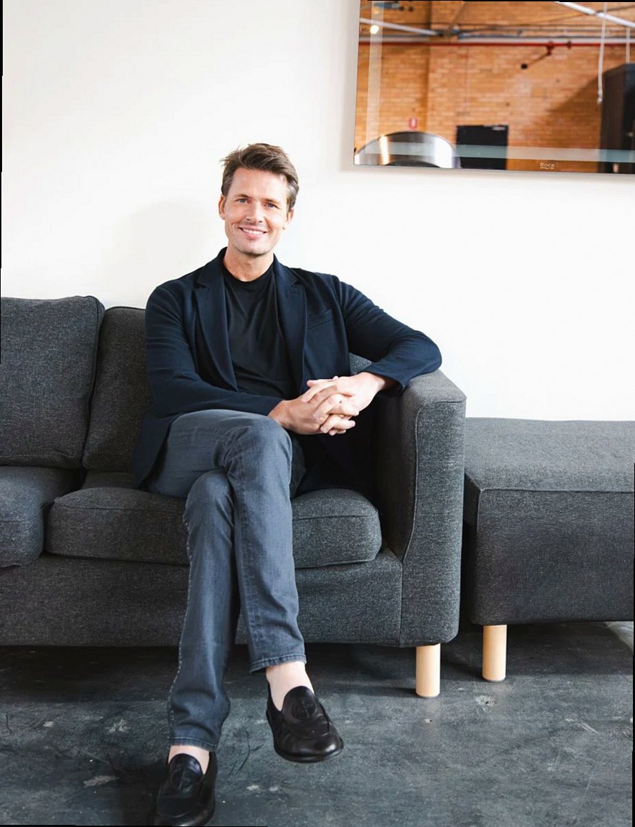 Portrait of a smiling man seated on a couch in a modern office setting, highlighting professional ambiance.